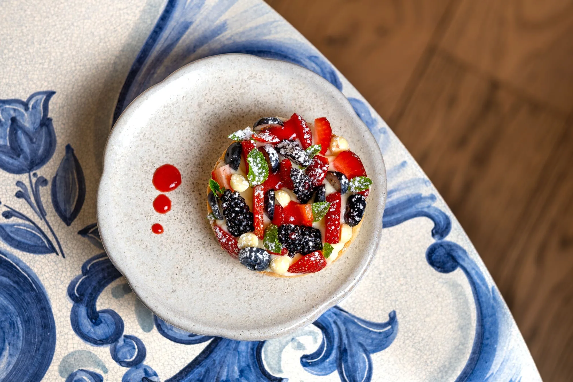 Tartaleta de frutos rojos sobre plato de cerámica y mesa de azulejo pintado a mano