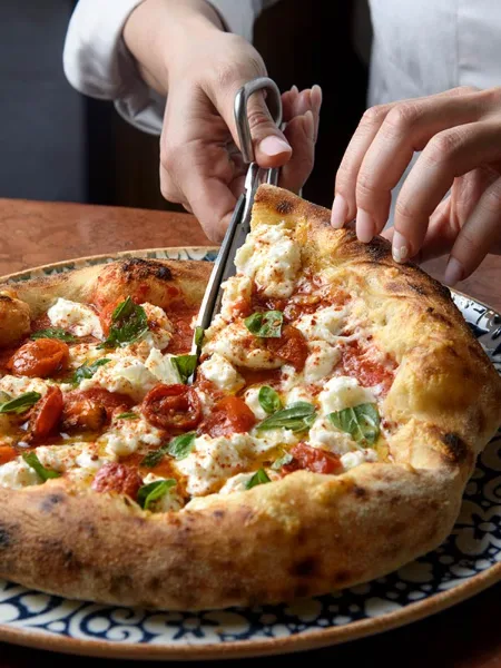 Pizza recién salida del horno con mozzarella y tomate